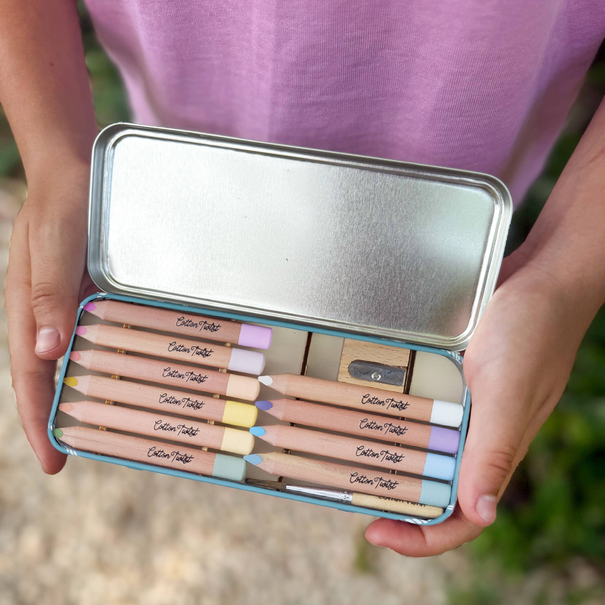 Watercolour pencils displayed in open tin, outdoor setting