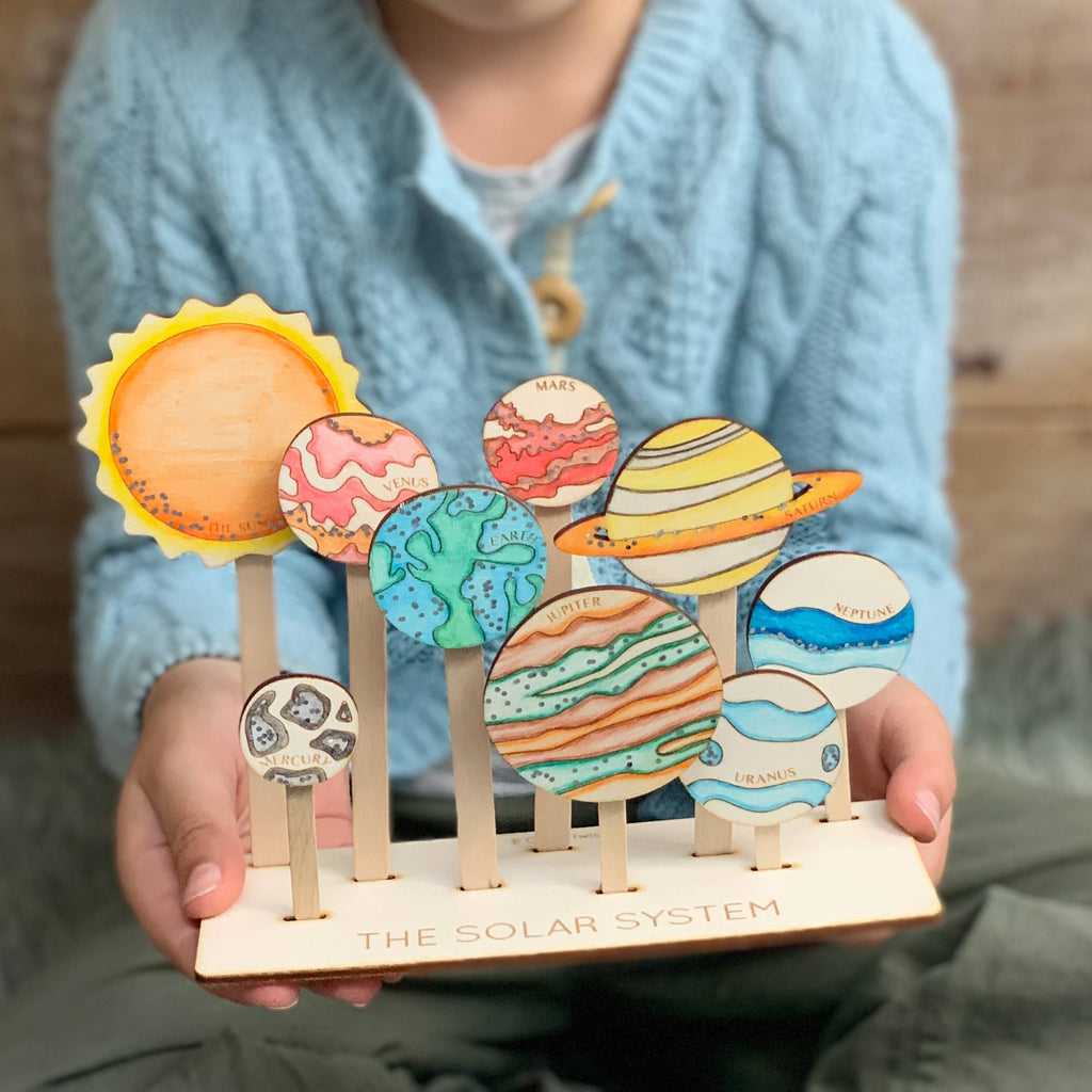 Child holding finished solar system wooden craft kit