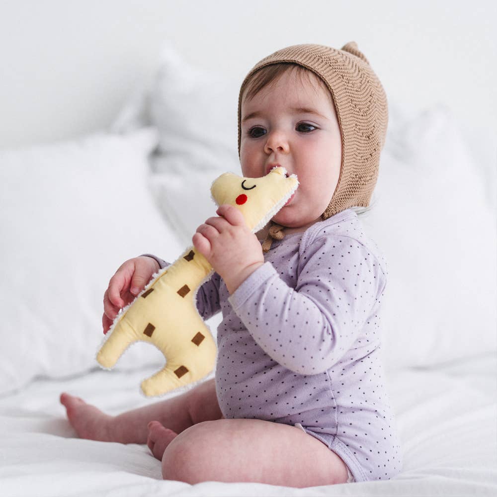 Baby teething on organic cotton giraffe rattle