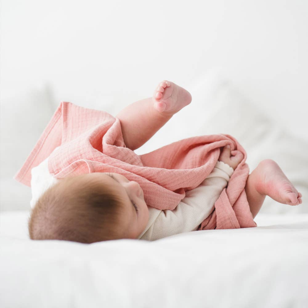 Newborn wrapped in organic cotton muslin blanket, pink