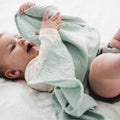 Baby playing with organic cotton muslin blanket