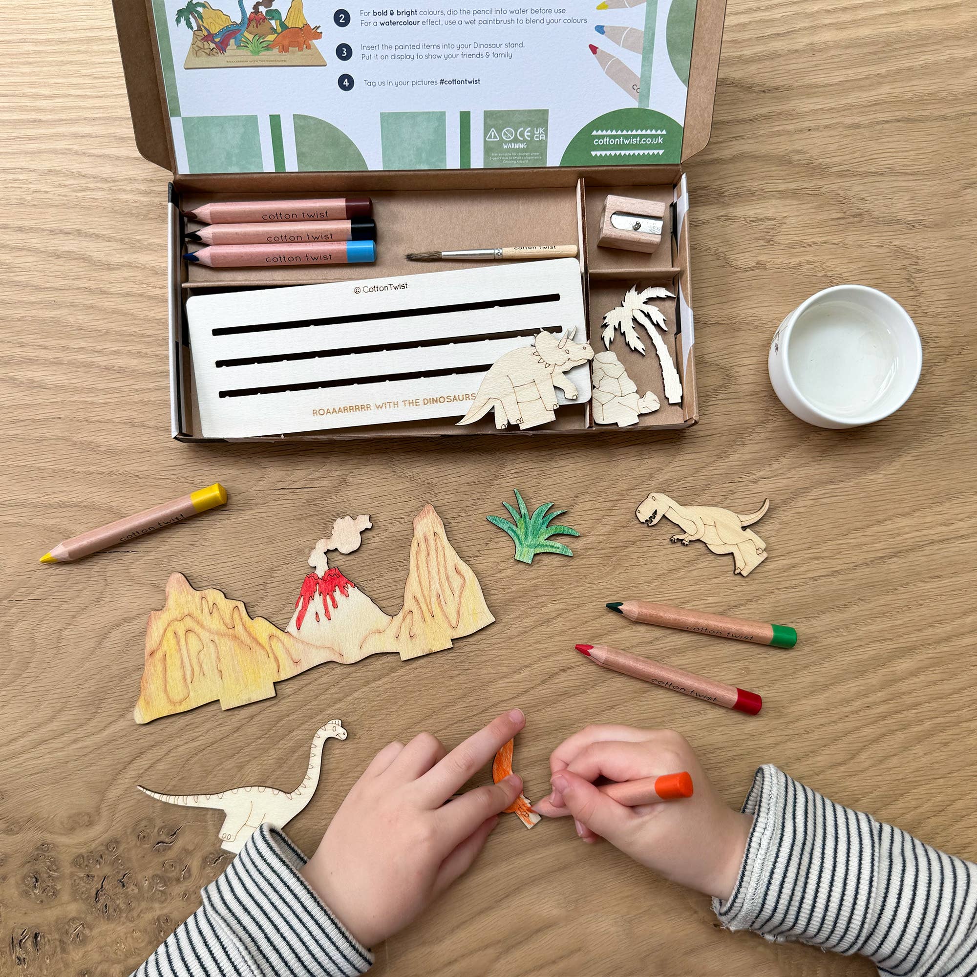 Child painting wooden dinosaur craft pieces