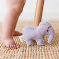 Baby standing with organic cotton elephant rattle