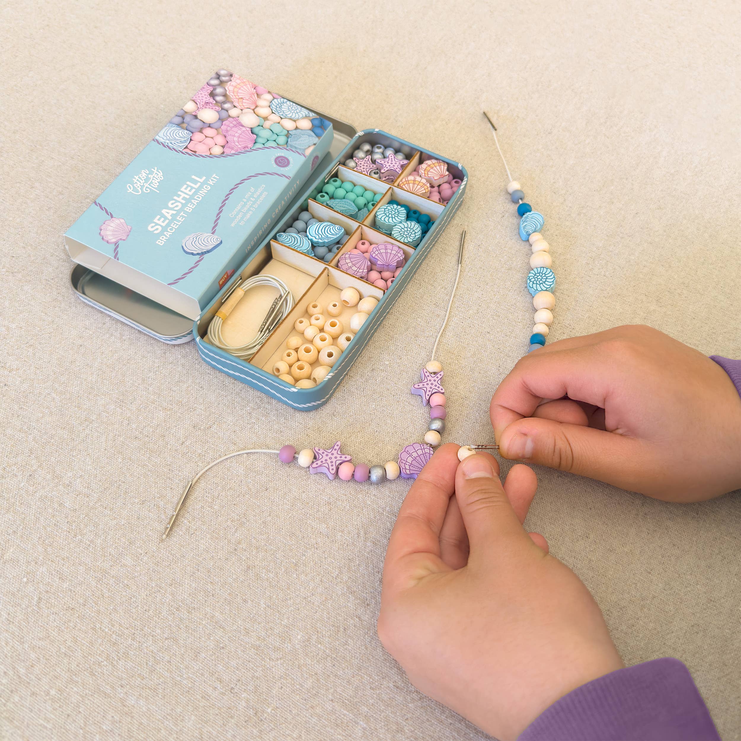 Child making a seashell bracelet with wooden beads