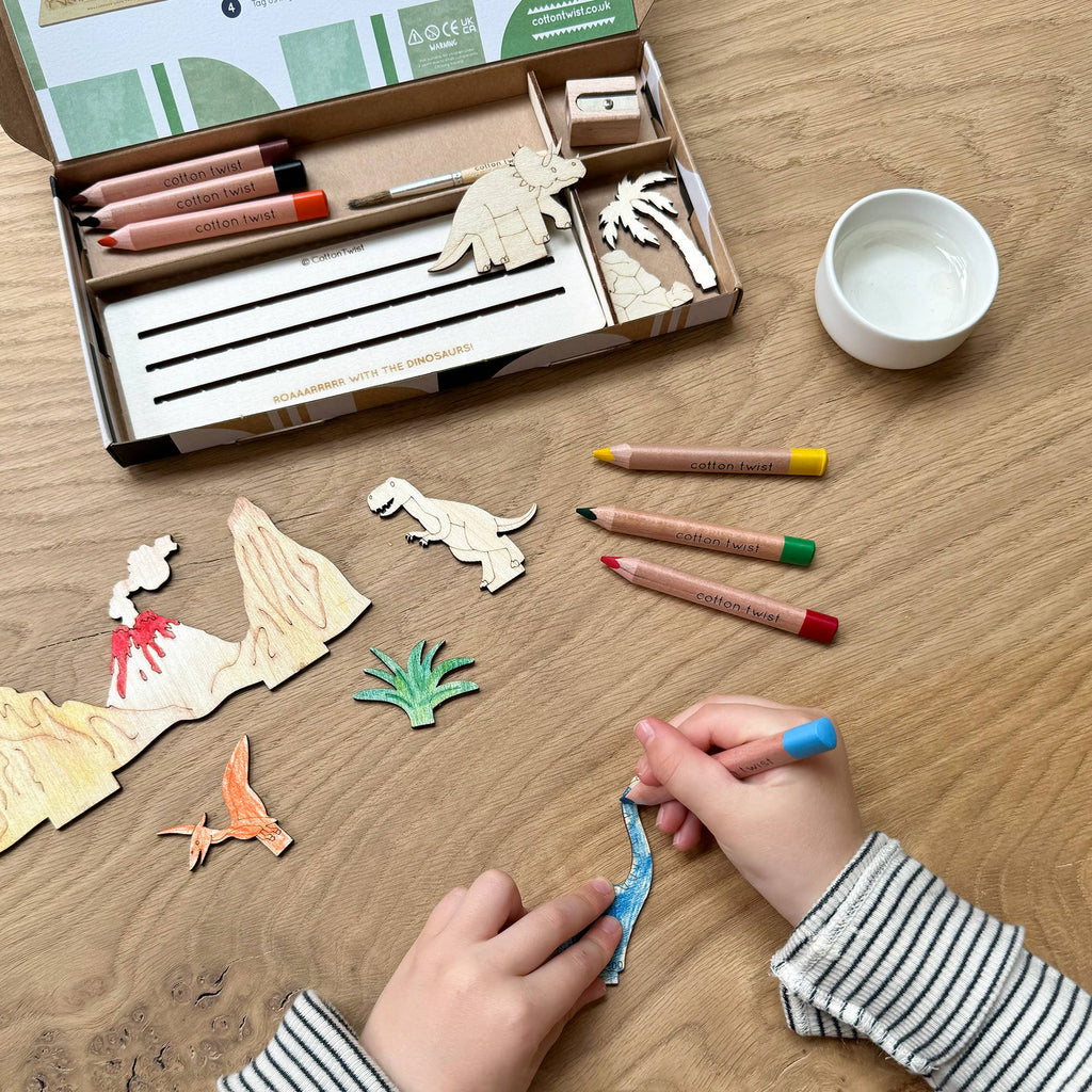 Child painting wooden dinosaur with watercolour pencils
